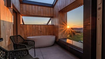 Et moderne udendørsareal med træterrasse, jacuzzi og et siddeområde med stole.