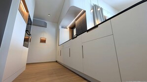 Een moderne keuken met witte kastjes, een houten vloer en inbouwspots.