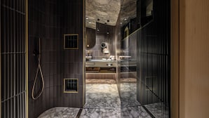 Een moderne badkamer met een marmeren vloer, een douche en een wastafel met spiegel.