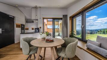 A modern kitchen with a dining area, large windows, and a view of the countryside.