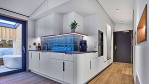 A modern kitchen with white cabinetry, a built-in island with a blue backsplash, and a skylight. - Modern design apartment with a view of the valley.<br>With sauna, roof terrace, outdoor bathtub and custom-made furnishings.<br>Perfect for two adults who appreciate peace and quality. (Breitenberg)
