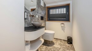 A modern bathroom with a marble sink, a toilet, and a window with blinds. - Modern design apartment with a view of the valley.<br>With sauna, roof terrace, outdoor bathtub and custom-made furnishings.<br>Perfect for two adults who appreciate peace and quality. (Breitenberg)