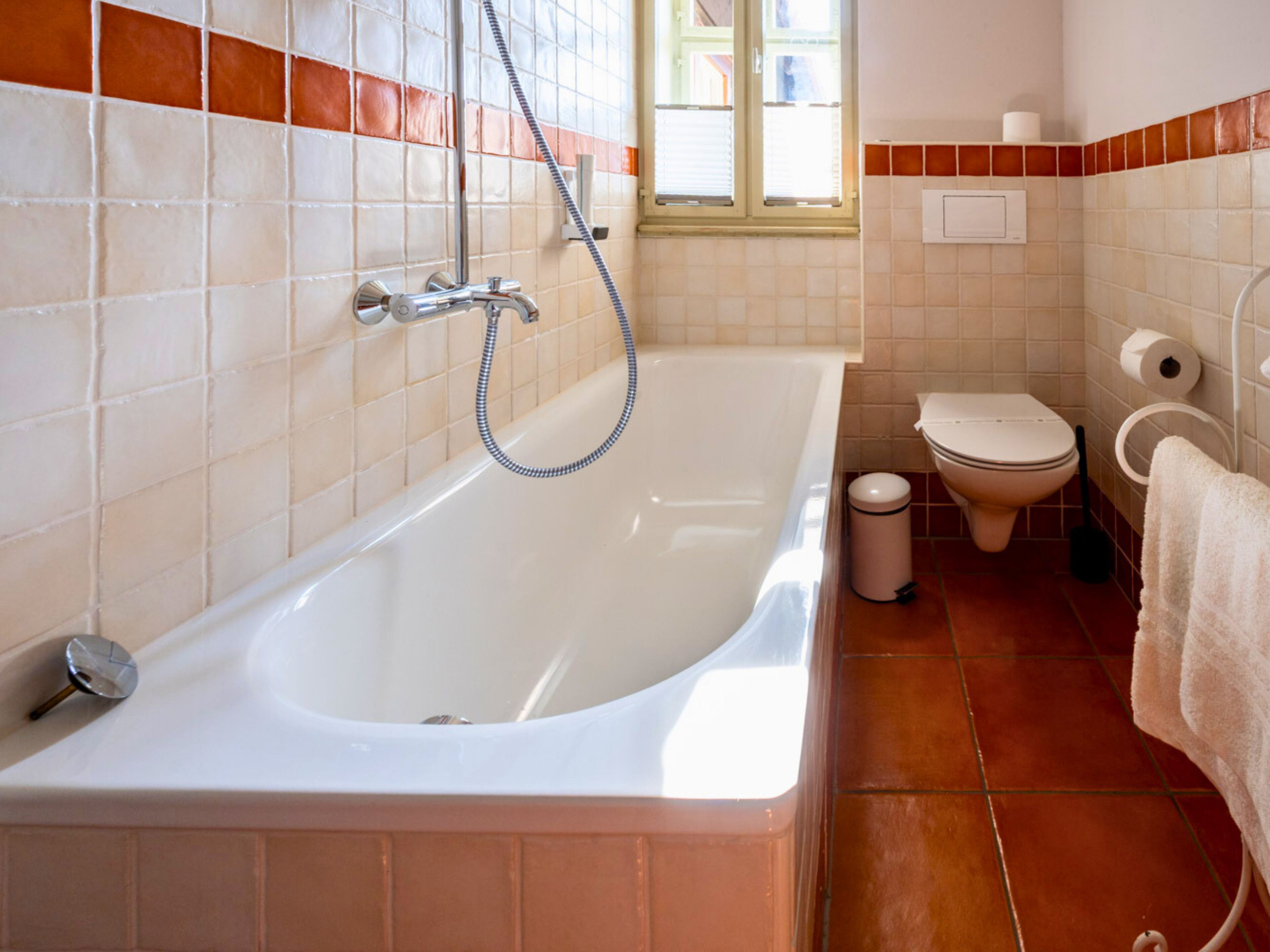 A bathroom with a bathtub, toilet, and a window.
