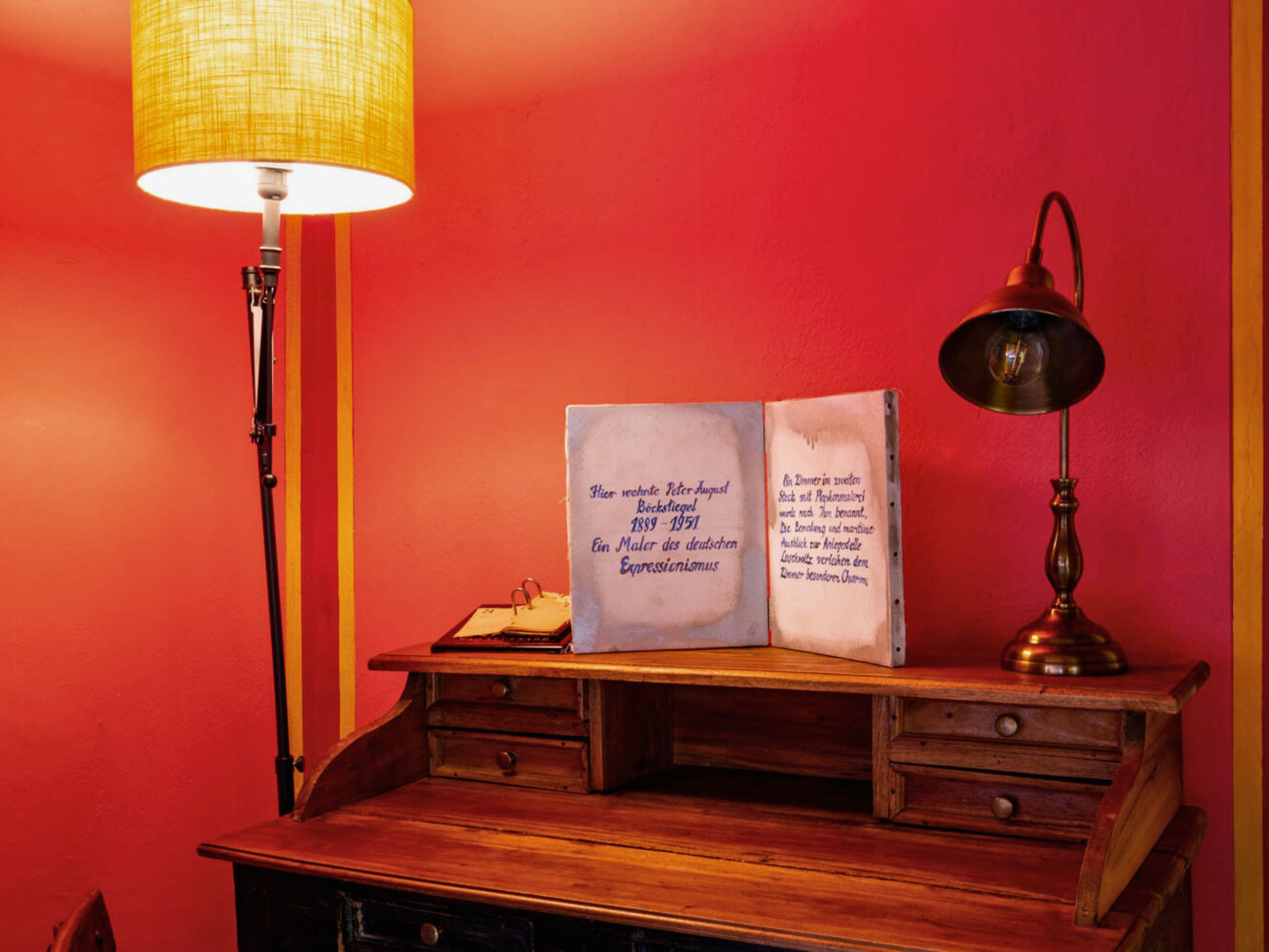A desk with a lamp, a book, and a lamp on the right side.