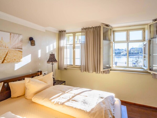 A bedroom with a bed, a lamp, a window with curtains, and a painting on the wall. - La Campagnola - Ristorante&Boutiquehotel (Dresden)