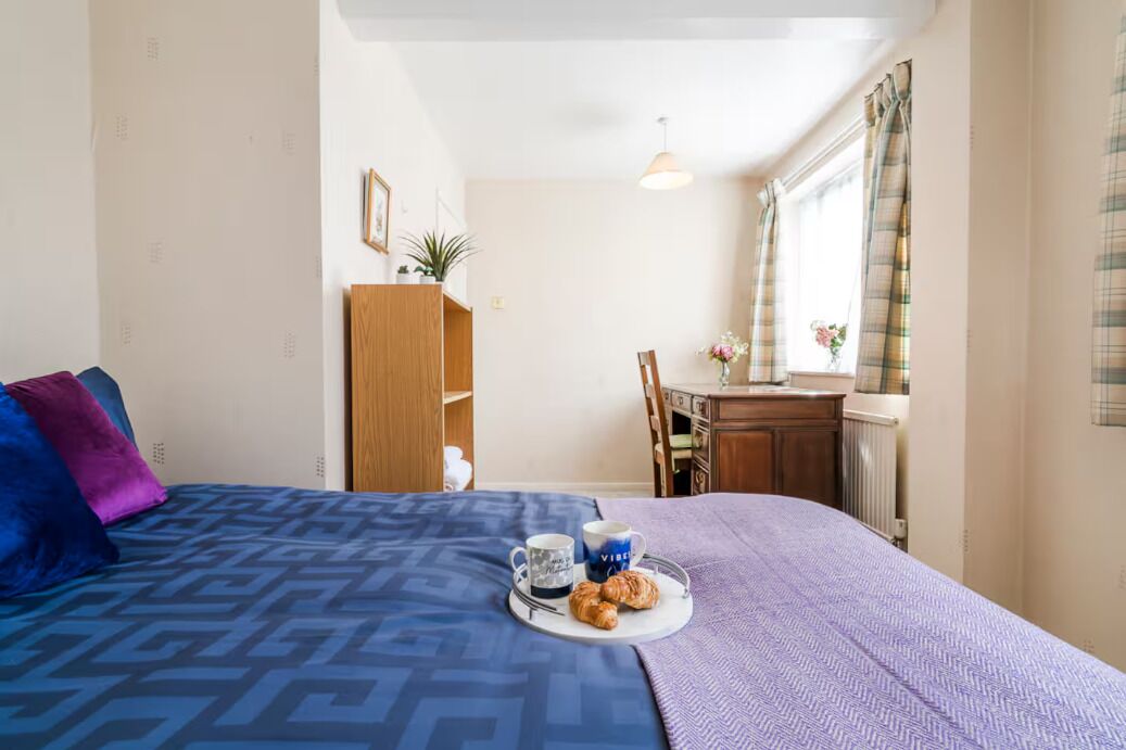 Una habitación de hotel con cama, escritorio y ventana con cortinas.