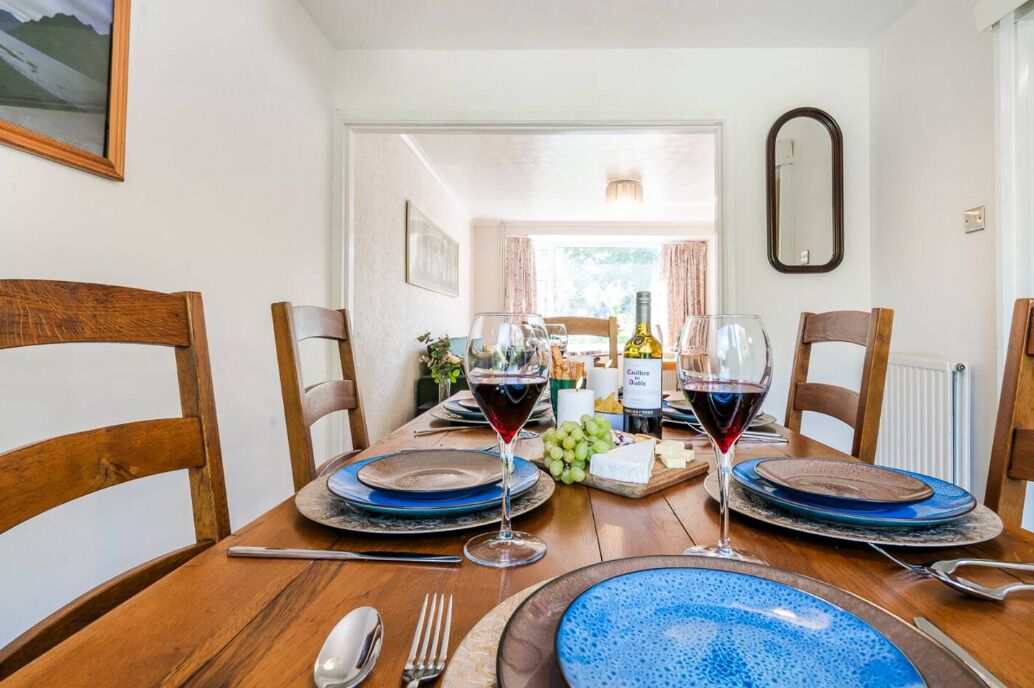 Een eettafel gedekt met blauwe borden, wijnglazen en een fles wijn.