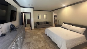 Une chambre d’hôtel avec un grand lit, un canapé, une télévision et un bureau avec un miroir.