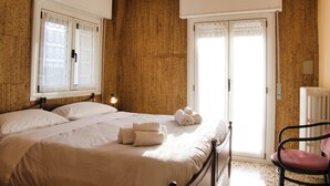 A bedroom with a bed, a chair, a radiator, and a window with curtains. - Garden - Pino Mugo - Two Bedroom Apartment, Sleeps 6 (Barzio)