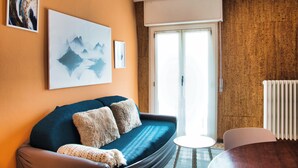 A cozy living room with a sofa, a small table, and a radiator. - Garden - Pino Mugo - Two Bedroom Apartment, Sleeps 6 (Barzio)