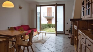Una cocina moderna con armarios de madera, una mesa de comedor con sillas, un sofá rojo y un balcón con vistas al exterior.