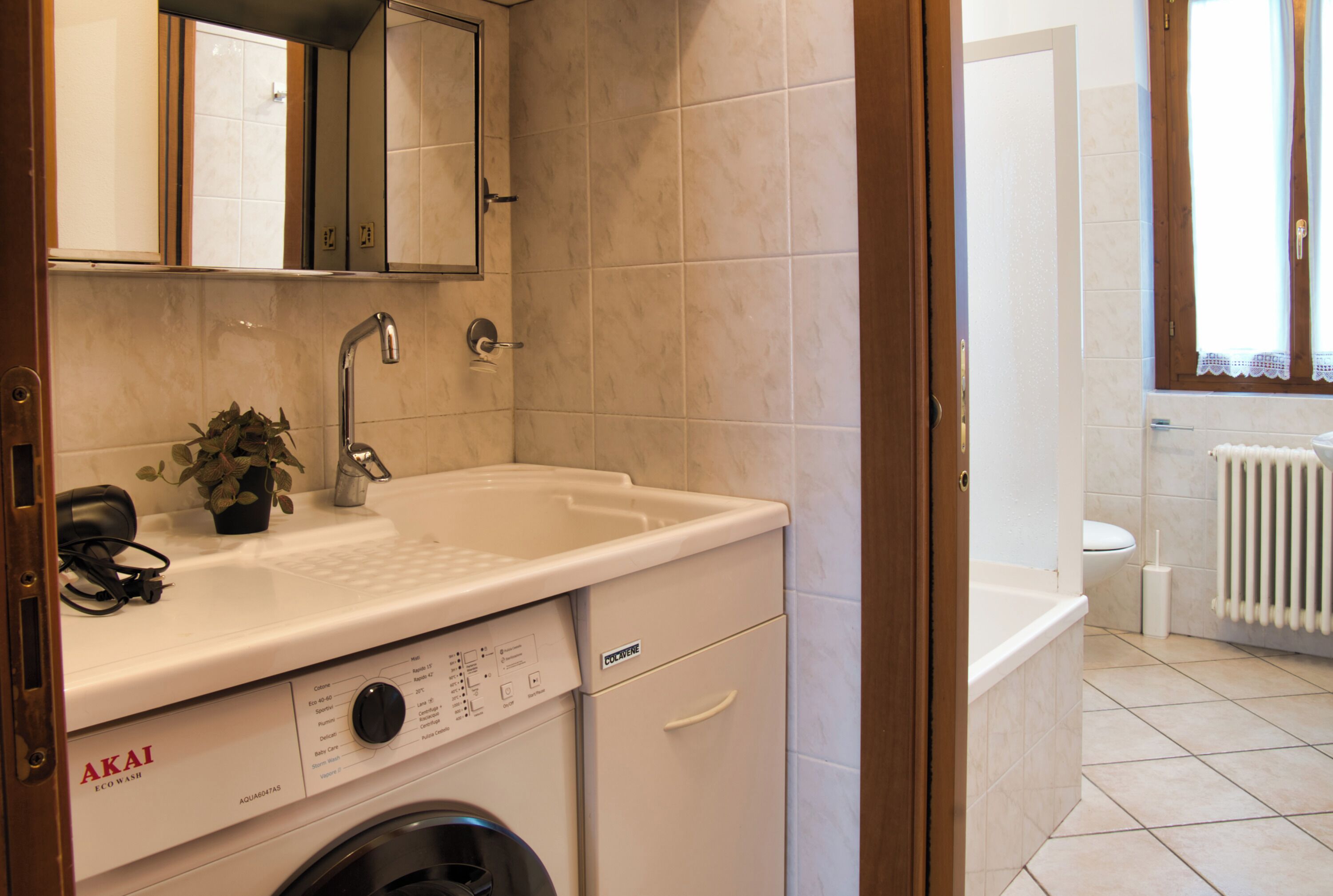 A compact bathroom with a sink, mirror, and a washing machine.