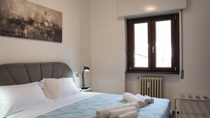 A bedroom with a bed, a nightstand, a window, and a radiator. - Cà Marta Vista Grigna (Moggio)