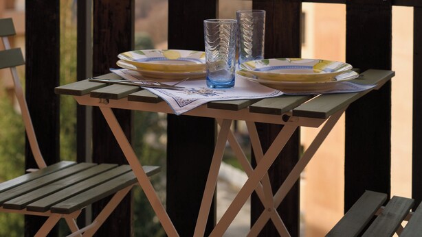A table with plates and glasses on a balcony overlooking a mountainous landscape. - Cà Marta Vista Grigna (Moggio)