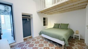 A bedroom with a bed, a wardrobe, a built-in shelf, and patterned flooring. - La Calade - Charming Apartment (Nîmes)