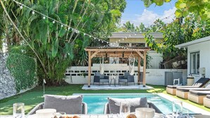 Ein Garten mit Pool, Sitzgelegenheit im Freien und einer Pergola.