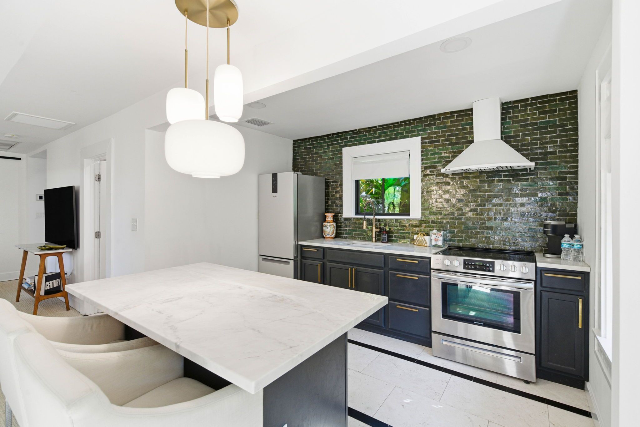 Et moderne køkken med en marmorø, rustfrie stålapparater og en backsplash i grøn mursten.