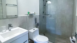 Ein modernes Badezimmer mit weißem Waschbecken, WC und einer Duschkabine.