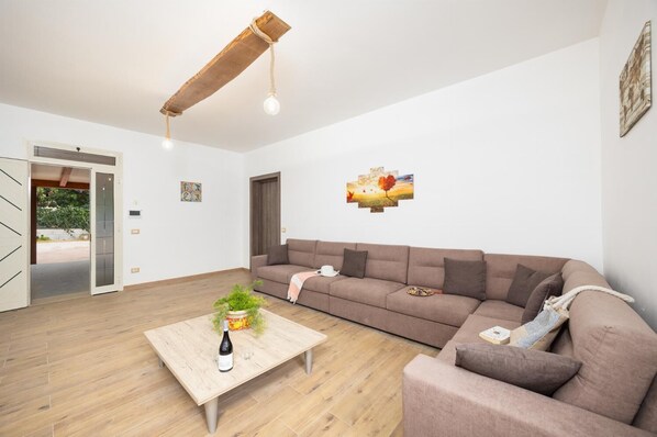 A modern living room with a wooden coffee table, a brown sofa, and a hanging light fixture.