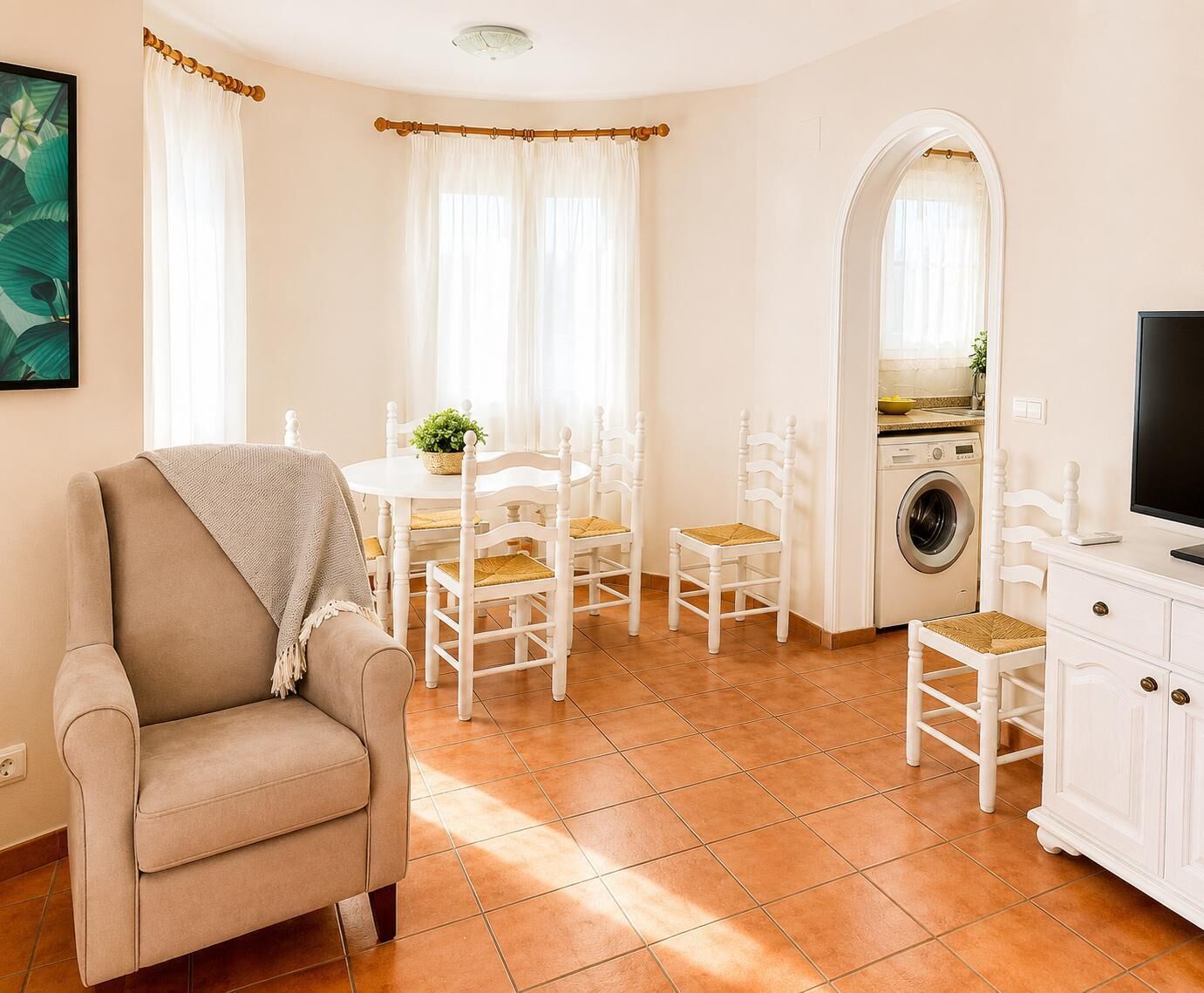 Un salon avec un canapé, une table à manger avec des chaises, un lave-linge et un téléviseur.