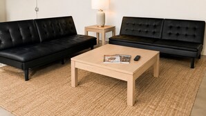 Ein Wohnzimmer mit zwei schwarzen Ledersofas, einem Holztisch als Couchtisch und einem Beistelltisch mit einer Lampe.