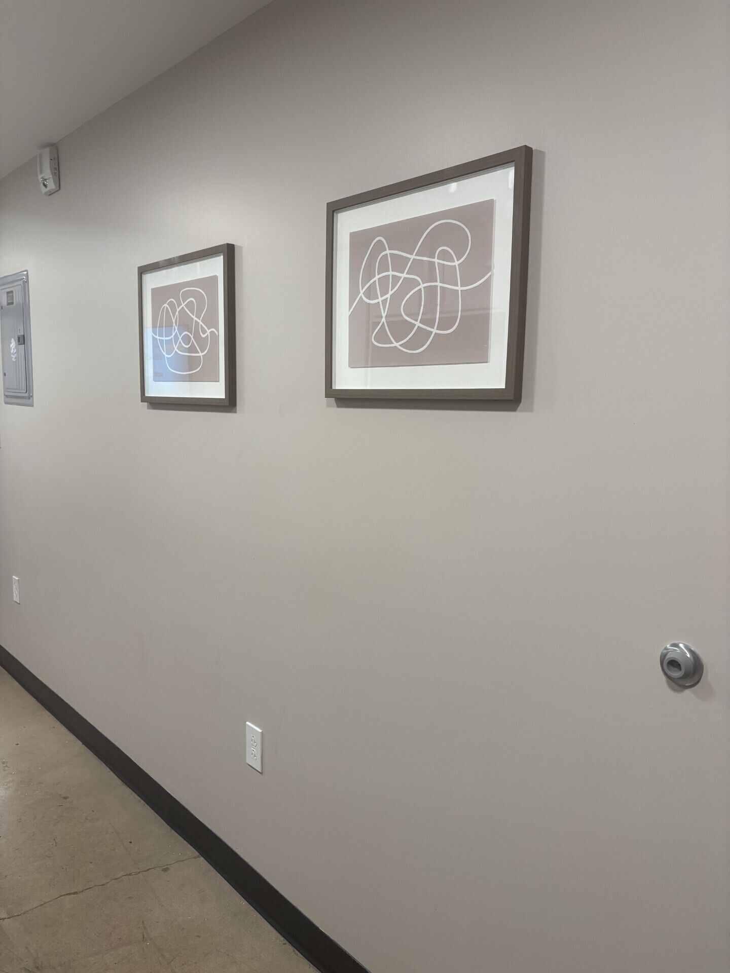 A hallway with three framed abstract artworks on the wall.