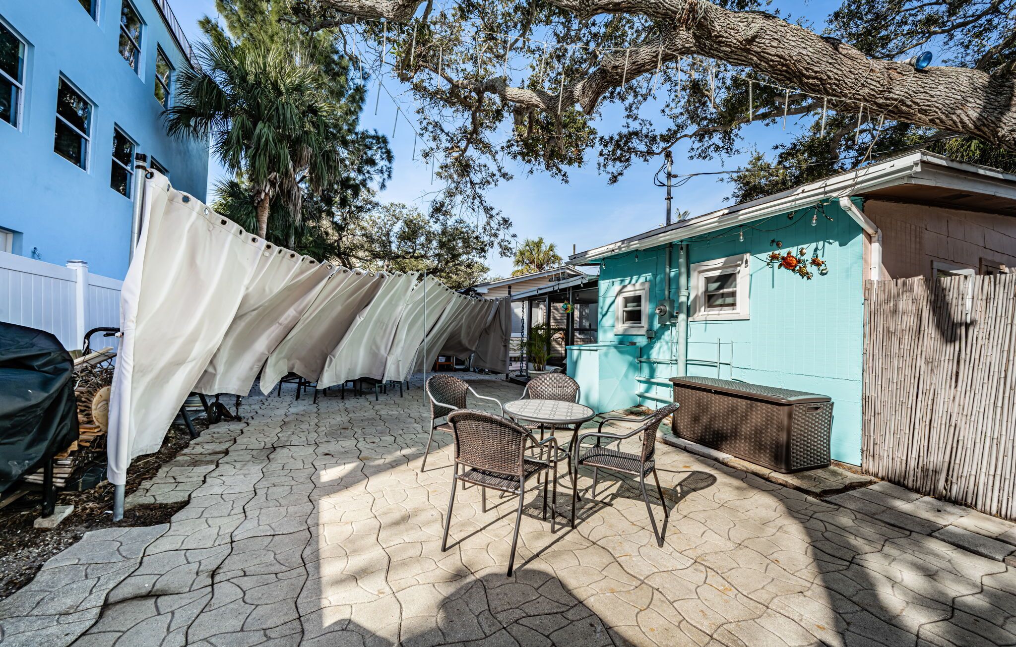 Une terrasse avec des meubles d’extérieur, un espace abrité et un bâtiment bleu.