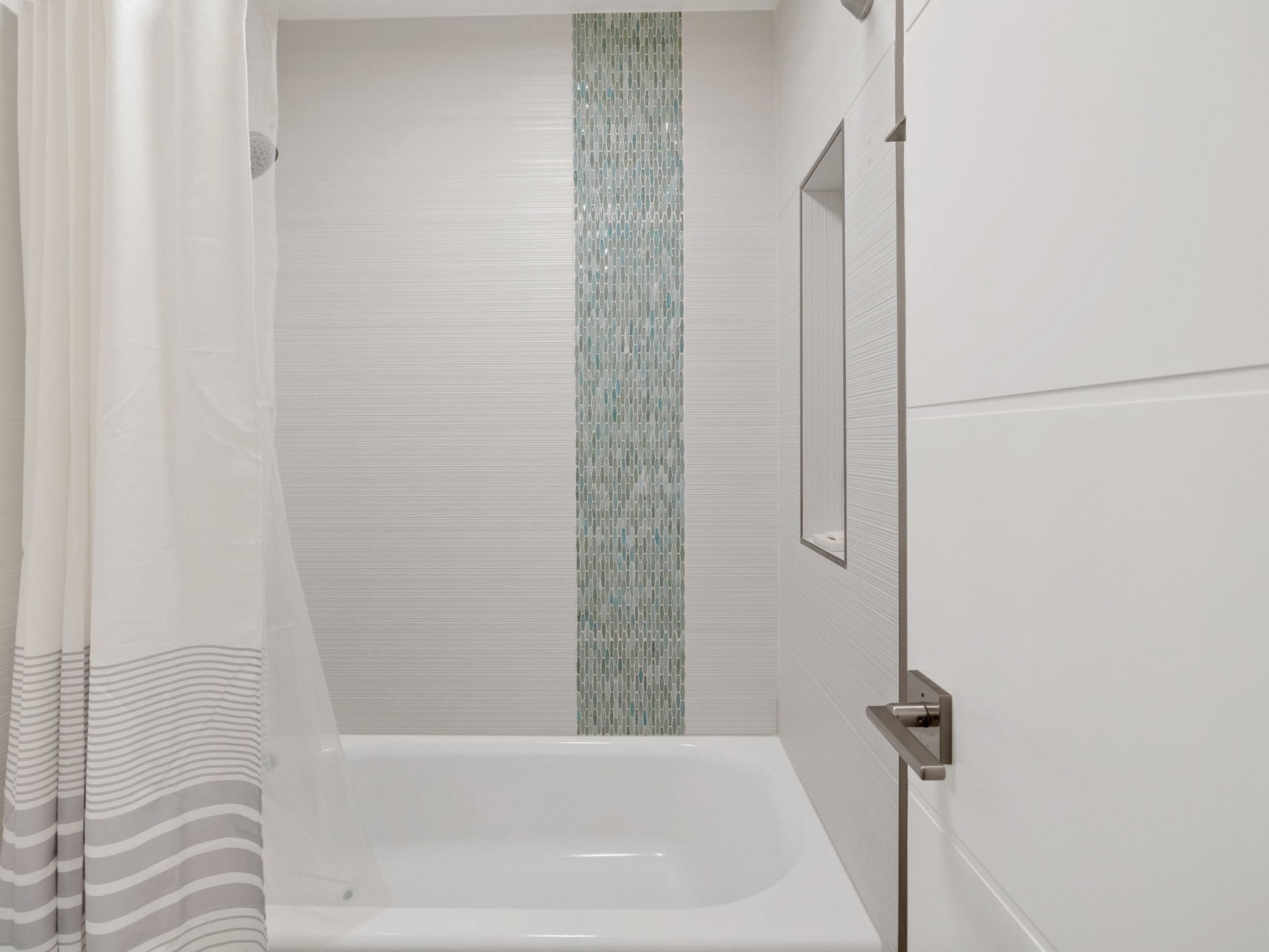 A modern bathroom with a bathtub, a shower curtain, and a mirror on the wall.