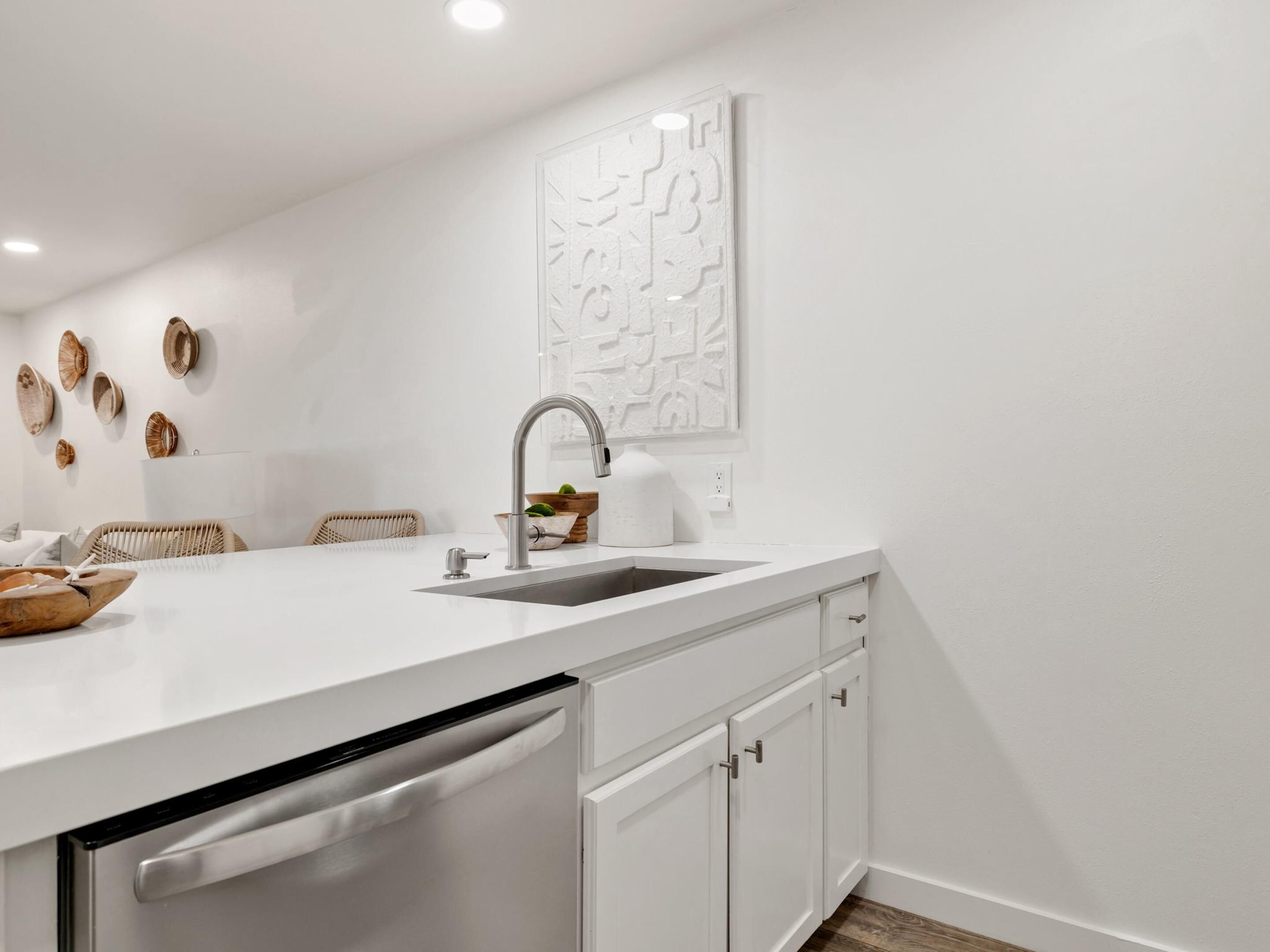 A modern kitchen with a white countertop, stainless steel appliances, and a decorative wall piece.