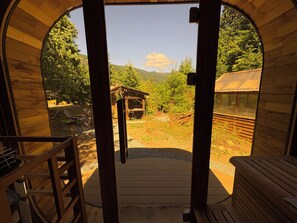 Une cabane en bois dotée d’une grande porte cintrée qui donne sur une terrasse.