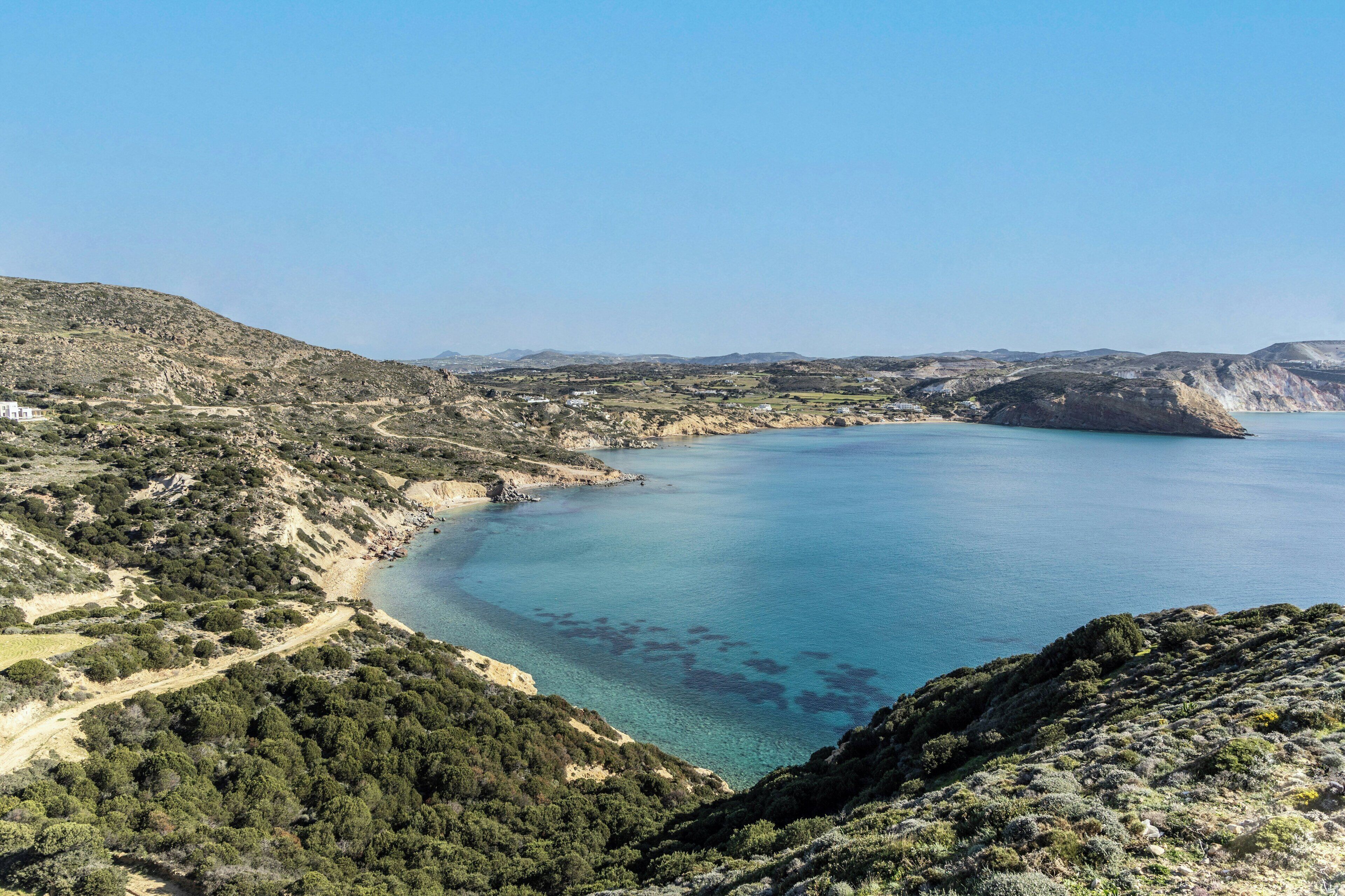 Un paisaje costero con vistas despejadas al mar, un camino sinuoso y vegetación escasa.
