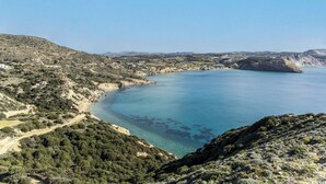 Un paysage côtier offrant une vue dégagée sur la mer, une route sinueuse et une végétation clairsemée.