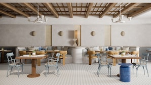 Un restaurant avec des tables et des chaises en bois, un plafond haut avec des poutres apparentes et un sol à motifs.