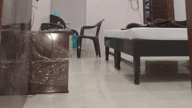 Une chambre comprenant un lit, un bureau, une chaise, un climatiseur et un téléviseur fixé au mur.