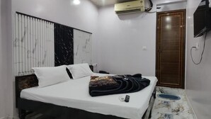 Une chambre à coucher comprenant un lit, un téléviseur, un appareil de climatisation et une porte.