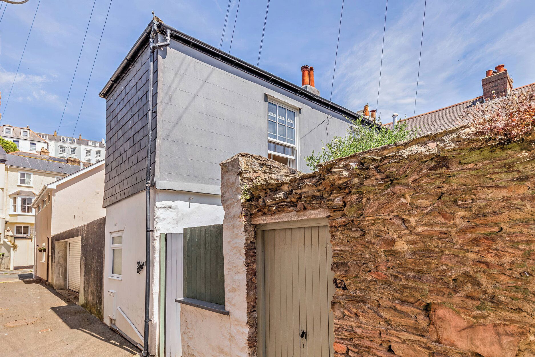 Un edificio con muro de piedra y una extensión moderna.