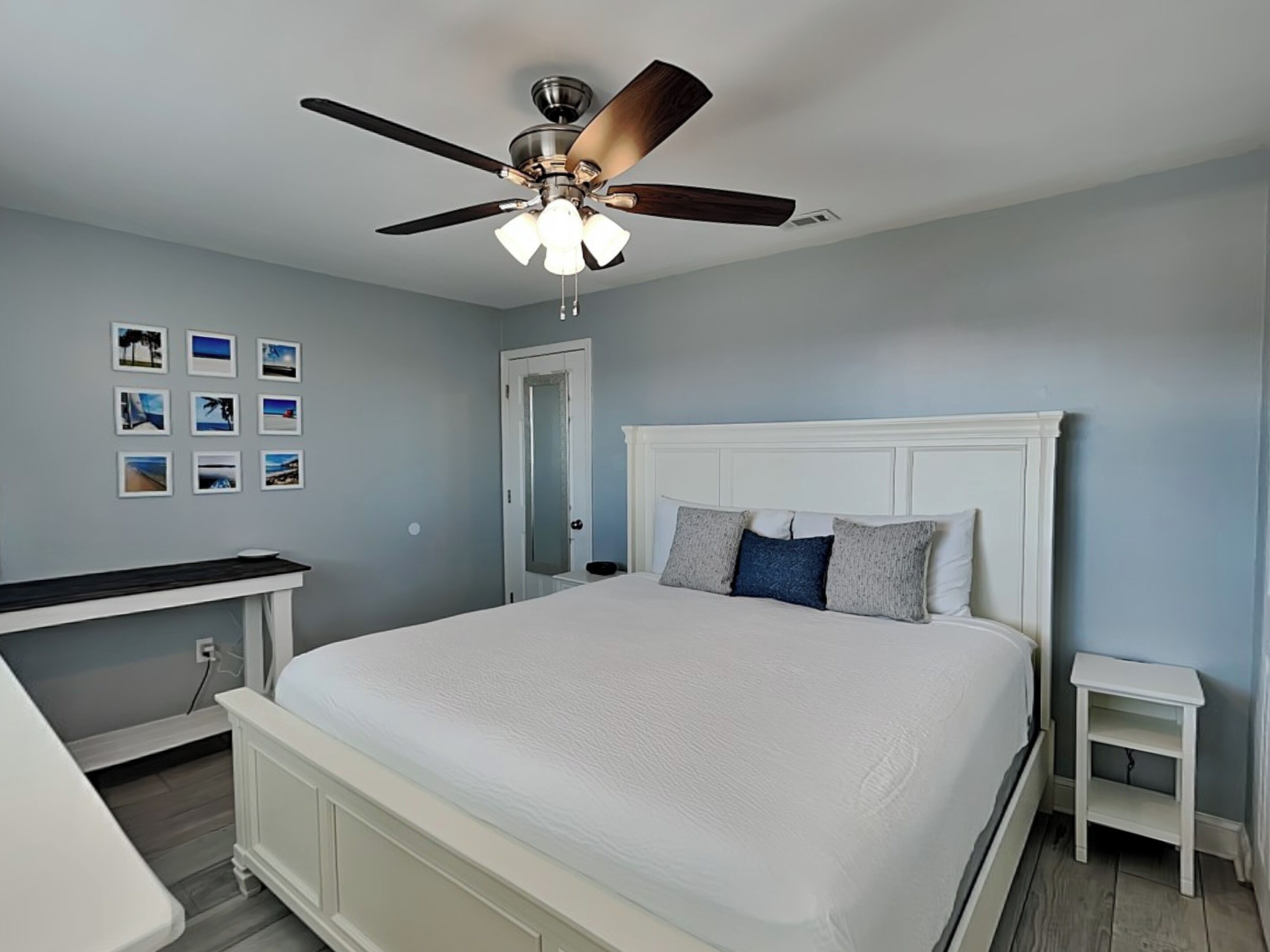 Une chambre à coucher comprenant un lit, un ventilateur de plafond, une table de chevet et une étagère fixée au mur.
