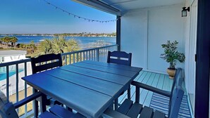 A balcony with a table and chairs, overlooking a body of water with a distant shoreline. - Treasure Cove #d308 - Paradise City (Panama City Beach)