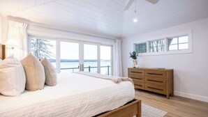 Een slaapkamer met een groot bed, een houten dressoir en uitzicht op de omgeving.