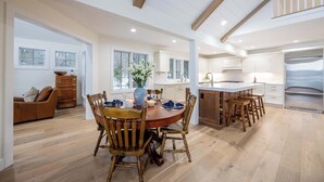 Een ruime keuken met houten vloeren, een eethoek met een ronde tafel en stoelen, en een moderne koelkast.