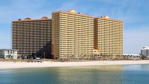 Un grande hotel con diversi piani e balconi, affacciato su una spiaggia e con vista sull'oceano.