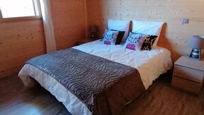 Une chambre dans une cabane en bois, avec un lit, des oreillers, une table de chevet et une fenêtre.