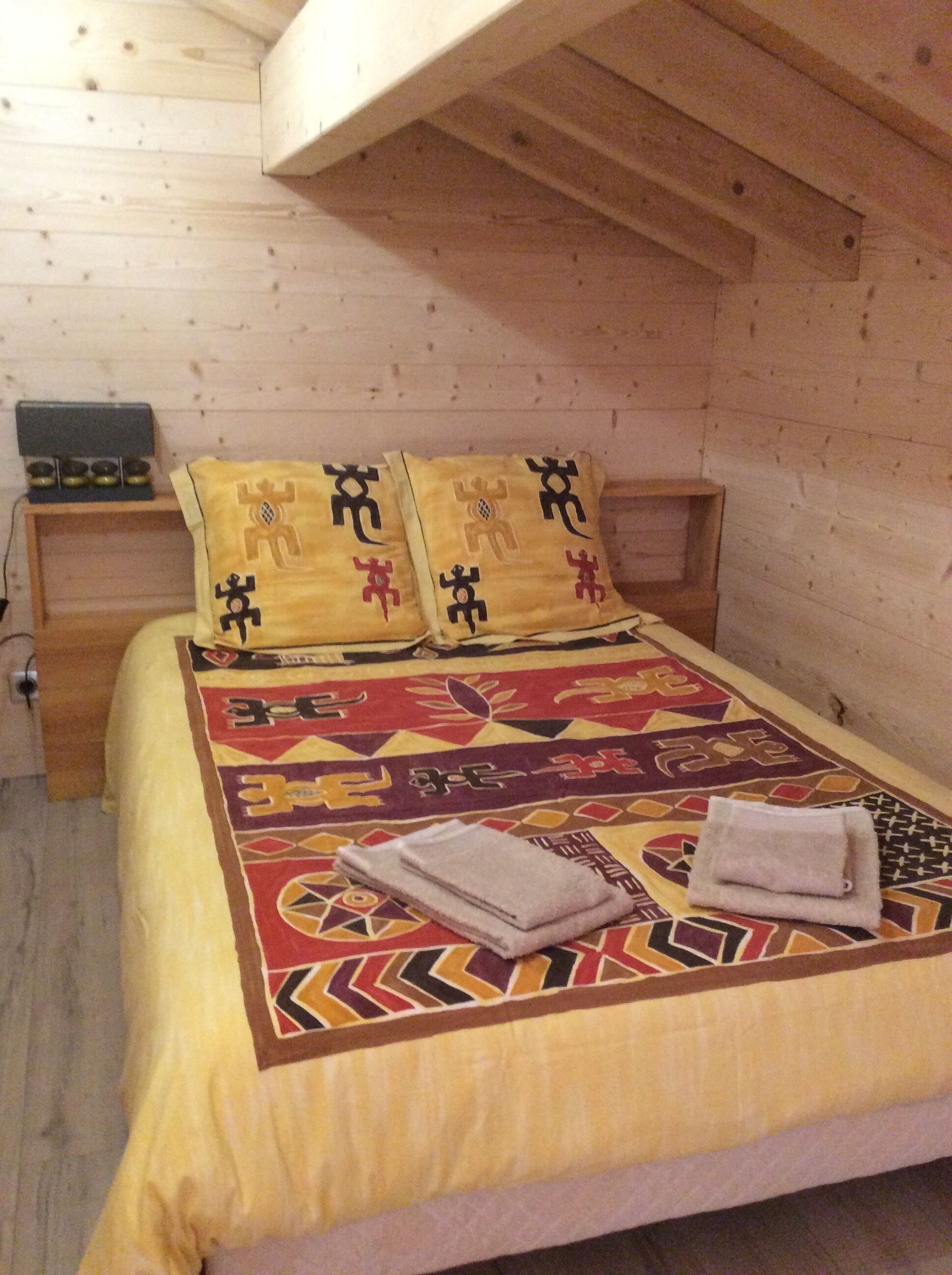 Ein Schlafzimmer einer Holzhütte mit Bett, Kissen und Nachttisch.