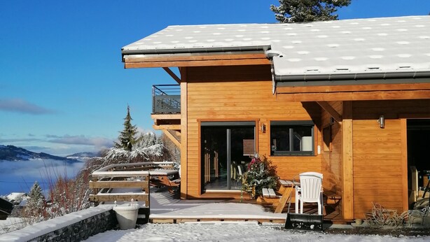 Une cabane en bois dotée d’un balcon, d’une terrasse couverte et offrant une vue sur les montagnes.