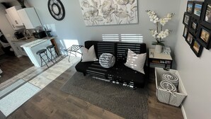 A modern living room with a black sofa, a coffee table, and a painting of flowers on the wall. - Unique 1-bdrm poolhouse with 24hr access to Pool & Jacuzzi (Phoenix)