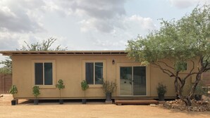 A single-story building with a flat roof, large windows, and a sliding glass door. There are potted plants placed in front of the windows and a tree to the right. - Unique 1-bdrm poolhouse with 24hr access to Pool & Jacuzzi (Phoenix)