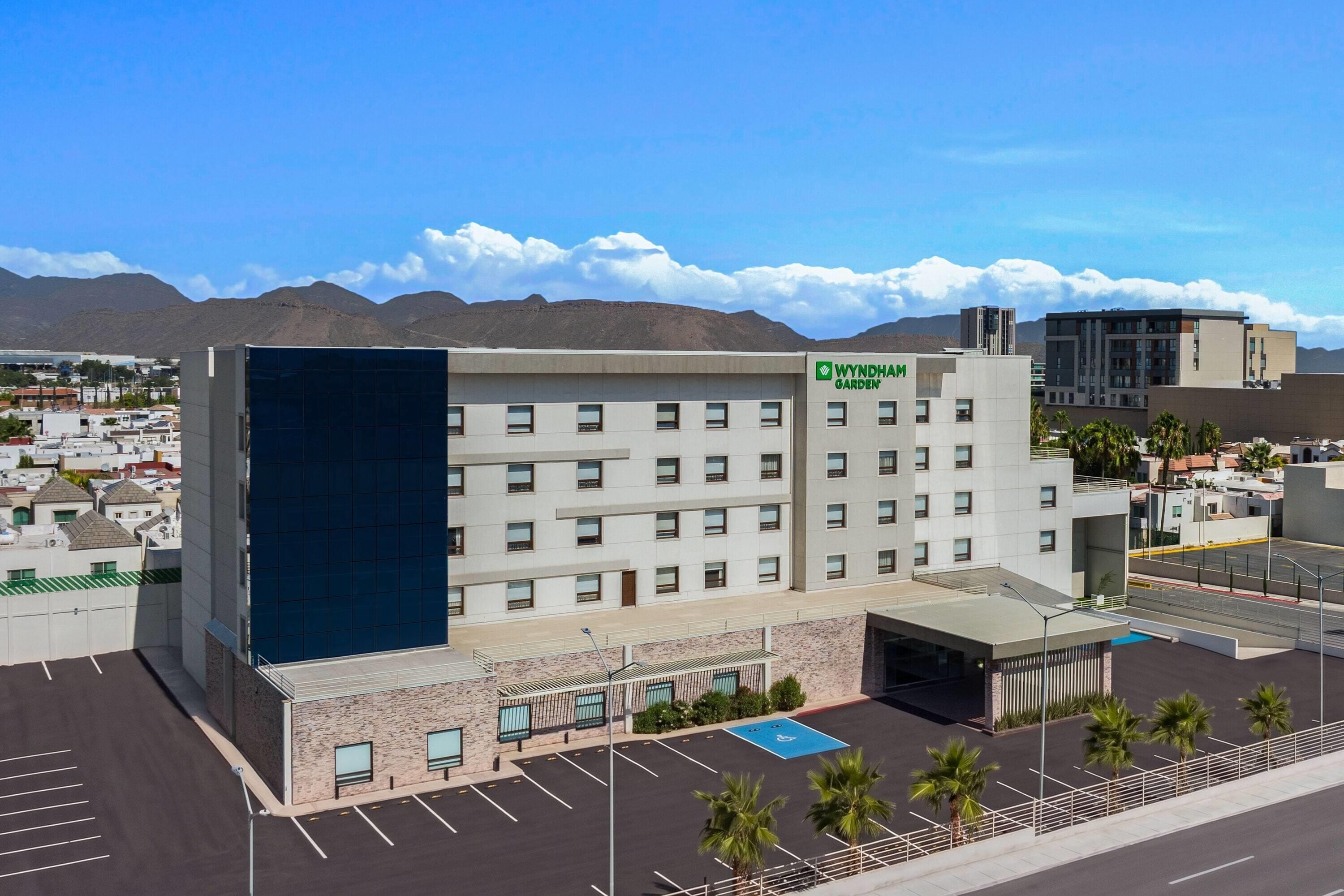 A Wyndham Garden hotel with a modern design, featuring a parking lot and a view of the surrounding area.