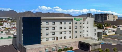 A Wyndham Garden hotel with a modern design, featuring a parking lot and a view of the surrounding area.