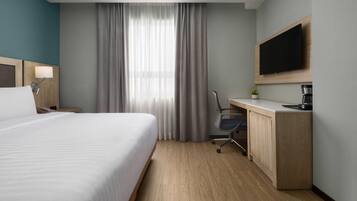 Une chambre d’hôtel équipée d’un lit, d’un bureau, d’une chaise, d’une télévision et d’une machine à café.