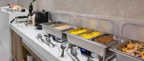 A buffet setup with various food items and utensils.